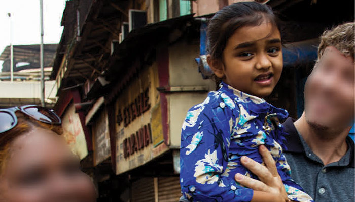 Young girl in India being held by a man on the street.