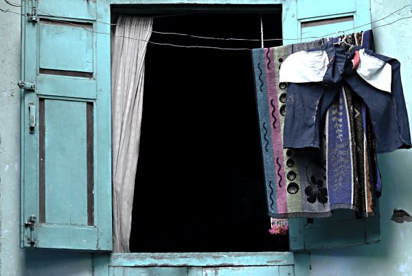 Blue door with shutters opened and laundry hanging on a line.